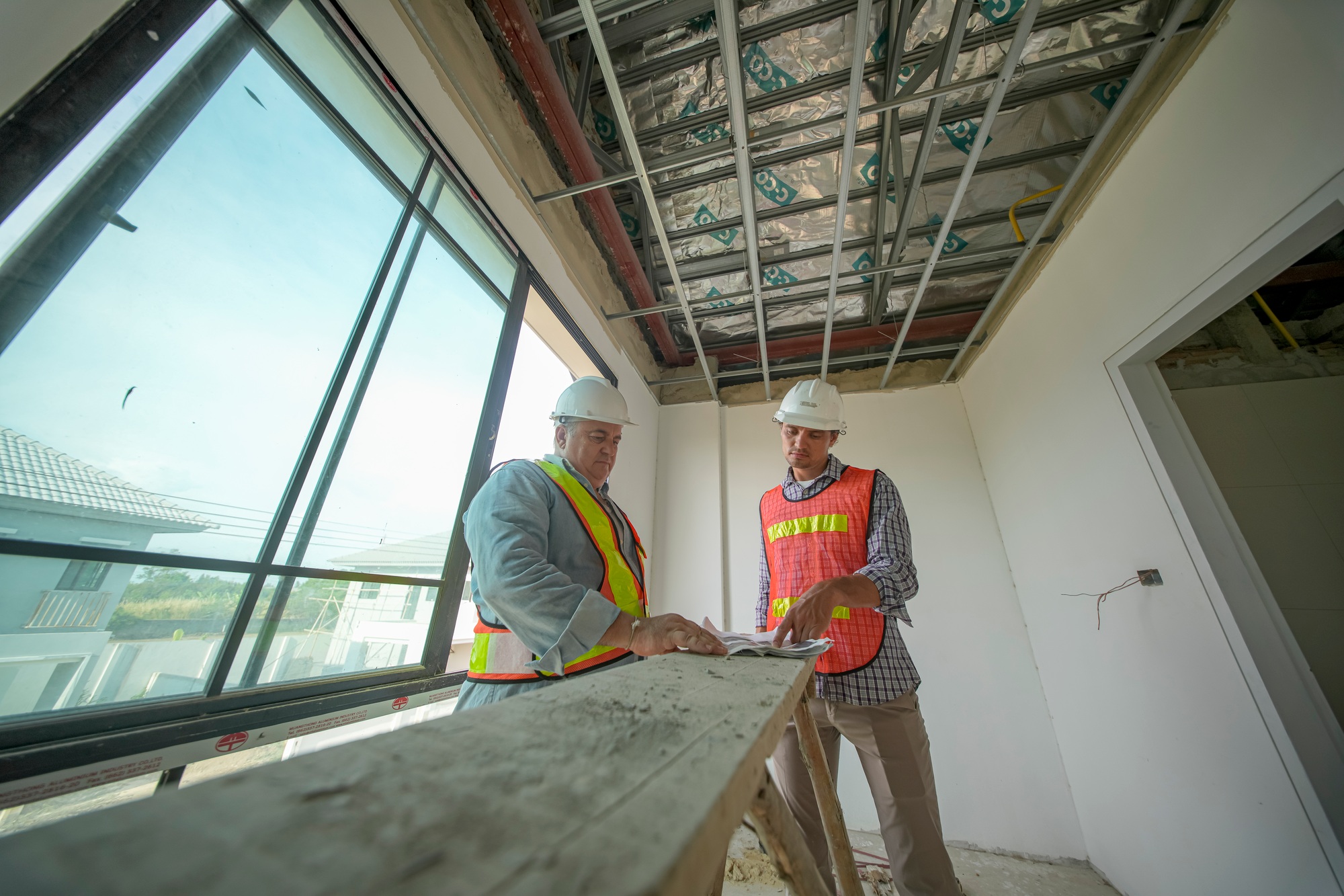 Construction workers collaborate on a project inside a new building during the day
