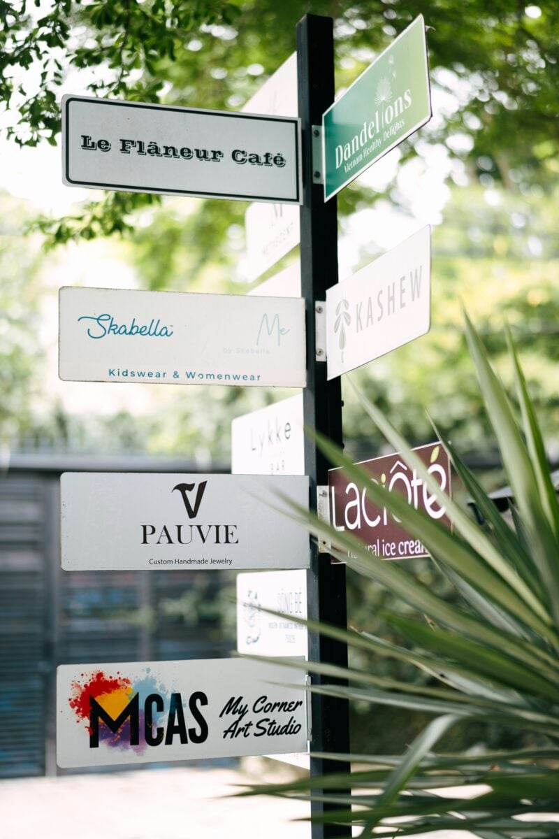 Signpost with various business names, including Le Flâneur Café, Skabella, and MCAS My Corner Art Studio.